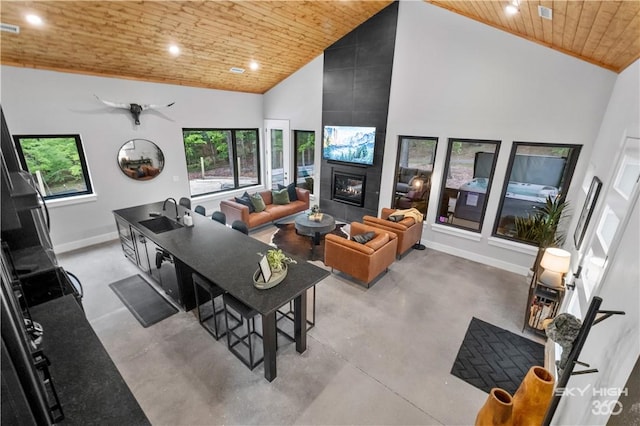 8775 Falls Hollow Rd, Rogers, AR 72756 - living area with wooden ceiling, baseboards, finished concrete flooring, high vaulted ceiling, and a tiled fireplace