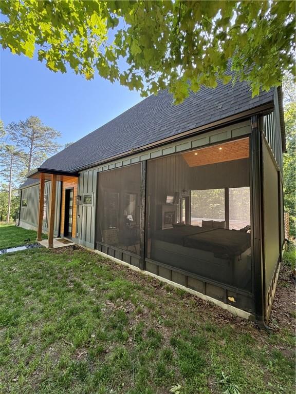 8775 Falls Hollow Rd, Rogers, AR 72756 - rear view of property with a sunroom, a shingled roof, board and batten siding, and a yard