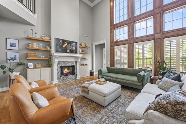 13 Dawn Hills Dr, Bentonville, AR 72712 - living room featuring wood finished floors, a towering ceiling, baseboards, a fireplace with flush hearth, and crown molding