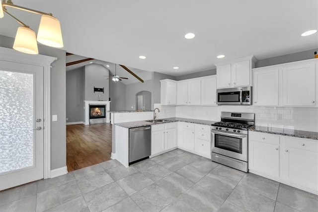 7326 Drury Ave, Springdale, AR 72762 - kitchen with appliances with stainless steel finishes, ceiling fan, dark stone counters, a glass covered fireplace, and open floor plan