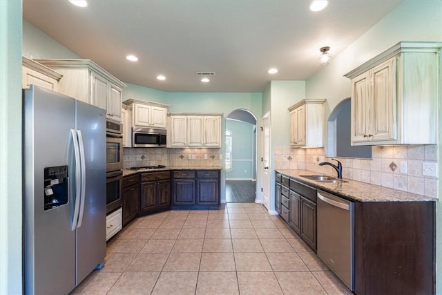 11029 Coleman Ct, Farmington, AR 72730 - kitchen featuring stainless steel appliances, arched walkways, a sink, light tile patterned floors, and decorative backsplash