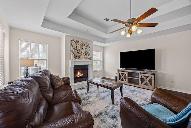 340 Mckissic Spring Rd, Centerton, AR 72719 - living room with ceiling fan, a raised ceiling, a warm lit fireplace, and baseboards