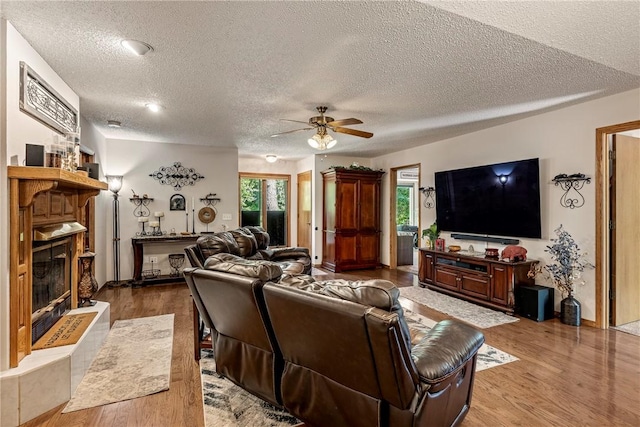 12 Drayton Ln, Bella Vista, AR 72715 - living area featuring a ceiling fan, a textured ceiling, a glass covered fireplace, wood finished floors, and healthy amount of natural light
