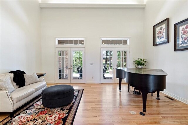 1325 Avery Pl, Siloam Springs, AR 72761 - living area featuring french doors, light wood-style flooring, a towering ceiling, and baseboards