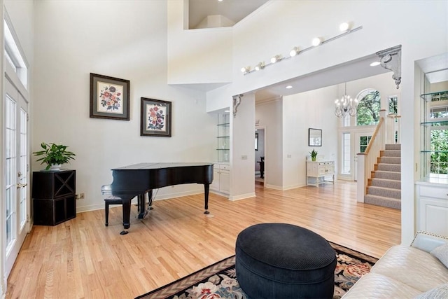 1325 Avery Pl, Siloam Springs, AR 72761 - living area featuring a high ceiling, light wood-style flooring, a chandelier, stairs, and baseboards
