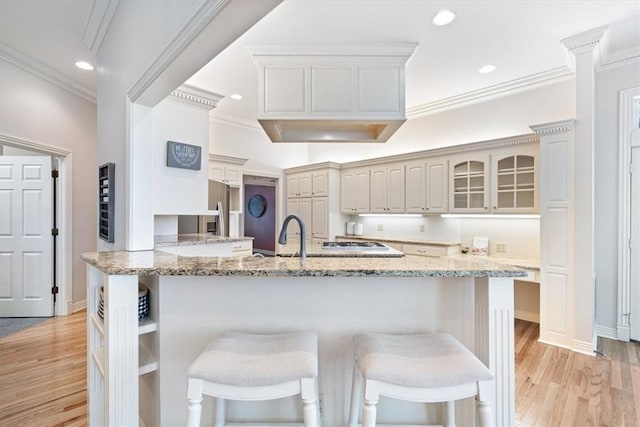 1325 Avery Pl, Siloam Springs, AR 72761 - kitchen with ornamental molding, light wood finished floors, a breakfast bar, light stone countertops, and recessed lighting