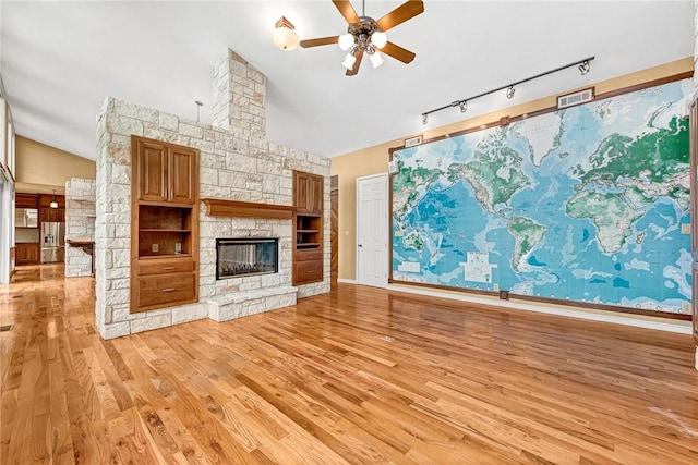 289 County Road 1521, Eureka Springs, AR 72632 - unfurnished living room featuring lofted ceiling, a ceiling fan, light wood-type flooring, a fireplace, and rail lighting
