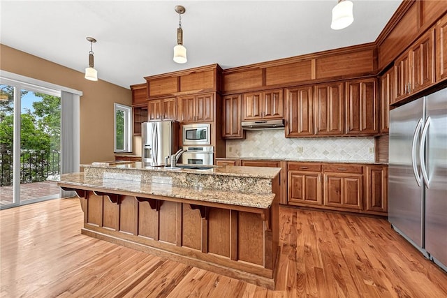 289 County Road 1521, Eureka Springs, AR 72632 - kitchen with appliances with stainless steel finishes, under cabinet range hood, decorative backsplash, light wood-type flooring, and a sink