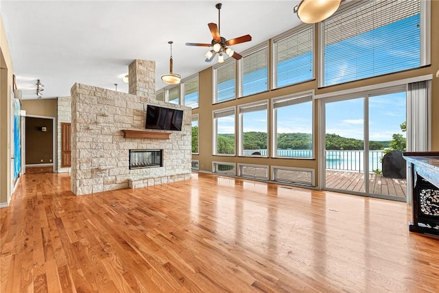 289 County Road 1521, Eureka Springs, AR 72632 - unfurnished living room featuring a fireplace, wood finished floors, ceiling fan, and a towering ceiling