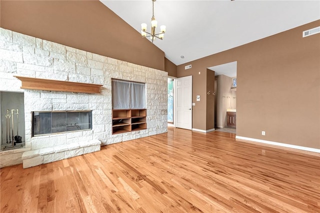 289 County Road 1521, Eureka Springs, AR 72632 - unfurnished living room with high vaulted ceiling, wood finished floors, a chandelier, baseboards, and a stone fireplace