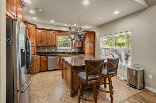 8 Allonby Cir, Bella Vista, AR 72714 - kitchen featuring appliances with stainless steel finishes, a kitchen island, backsplash, brown cabinets, and recessed lighting