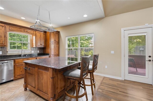 8 Allonby Cir, Bella Vista, AR 72714 - kitchen with stainless steel dishwasher, a kitchen island, brown cabinets, tasteful backsplash, and a kitchen breakfast bar