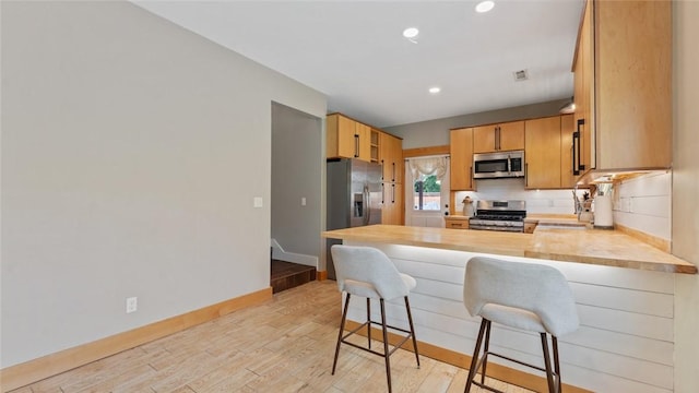 1806 Best Friend Ln, Fayetteville, AR 72704 - kitchen featuring appliances with stainless steel finishes, a peninsula, light countertops, light wood-style flooring, and recessed lighting