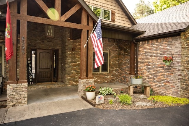 8295 Ridgecrest Ln, Rogers, AR 72756 - property entrance with brick siding, a shingled roof, and a porch