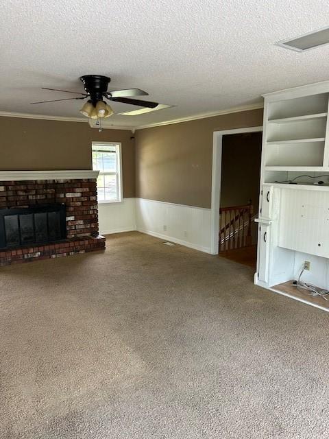 1103 NW 10th St, Bentonville, AR 72712 - unfurnished living room featuring carpet, ornamental molding, a textured ceiling, a ceiling fan, and wainscoting