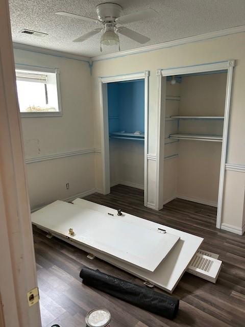 1103 NW 10th St, Bentonville, AR 72712 - unfurnished bedroom featuring multiple closets, a textured ceiling, dark wood-style floors, crown molding, and ceiling fan