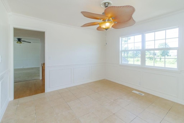 1103 NW 10th St, Bentonville, AR 72712 - empty room with a ceiling fan, a decorative wall, crown molding, wainscoting, and light tile patterned floors