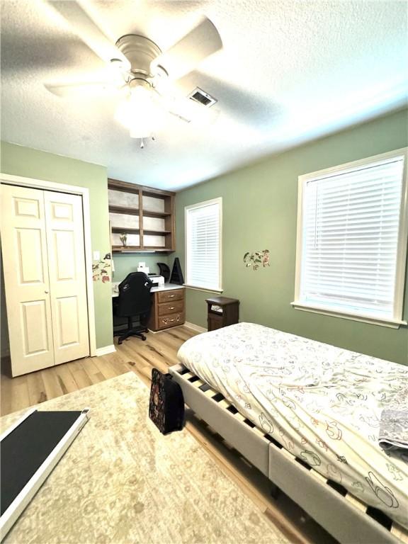 904 Deerfield Ct, Russellville, AR 72801 - bedroom featuring light wood-style floors, a closet, a desk, a textured ceiling, and ceiling fan