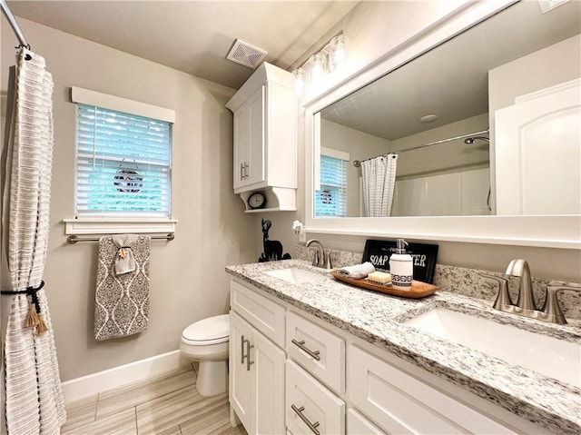 219 Kinross Dr, Bella Vista, AR 72715 - full bathroom with baseboards, toilet, plenty of natural light, and double vanity