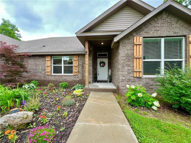 219 Kinross Dr, Bella Vista, AR 72715 - view of exterior entry featuring brick siding and a shingled roof