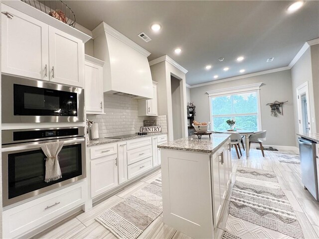 219 Kinross Dr, Bella Vista, AR 72715 - kitchen with stainless steel appliances, crown molding, white cabinetry, decorative backsplash, and a kitchen island