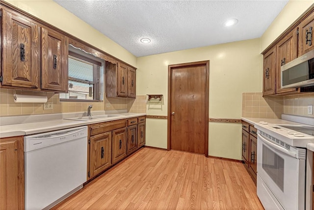 2001 W Magnolia St, Rogers, AR 72758 - kitchen with white appliances, a sink, a textured ceiling, light wood-style floors, and tasteful backsplash