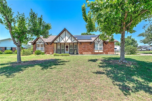 2001 W Magnolia St, Rogers, AR 72758 - tudor house featuring solar panels, a front yard, and brick siding