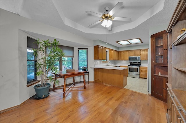 6 Runnymede Ln, Bella Vista, AR 72715 - kitchen featuring stainless steel appliances, a tray ceiling, a peninsula, light wood-type flooring, and light countertops