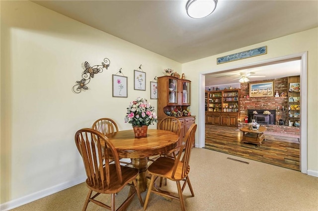 521 S 13th St, Rogers, AR 72758 - dining area featuring a fireplace, a ceiling fan, and baseboards