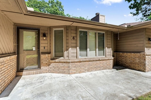 4 Wincanton Ln, Bella Vista, AR 72715 - doorway to property with a patio, a chimney, and brick siding