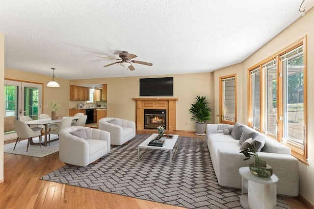 4 Wincanton Ln, Bella Vista, AR 72715 - living area with a textured ceiling, light wood-type flooring, a glass covered fireplace, and a ceiling fan