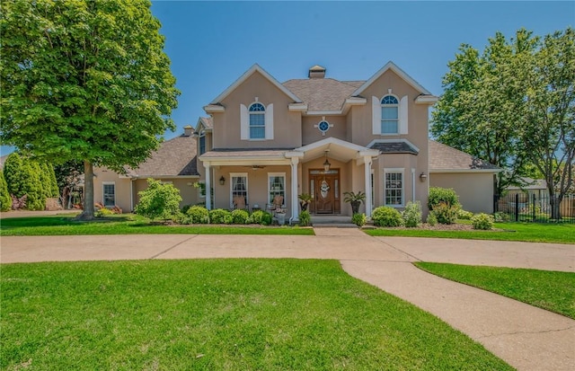 4 W Colonial Dr, Rogers, AR 72758 - traditional home featuring stucco siding, a chimney, covered porch, and a ceiling fan