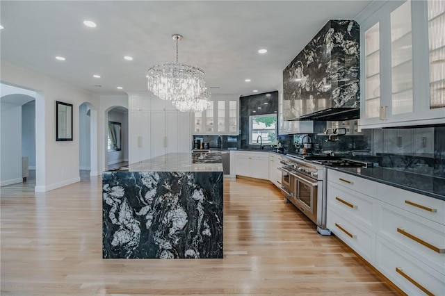4 W Colonial Dr, Rogers, AR 72758 - kitchen with double oven range, arched walkways, light wood-type flooring, a chandelier, and backsplash