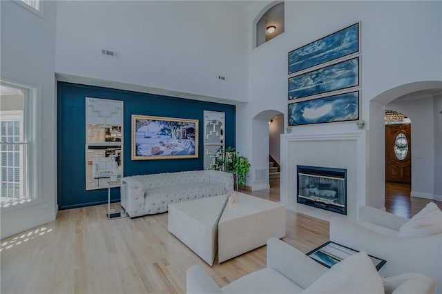 4 W Colonial Dr, Rogers, AR 72758 - living room with arched walkways, a high ceiling, wood finished floors, a glass covered fireplace, and plenty of natural light