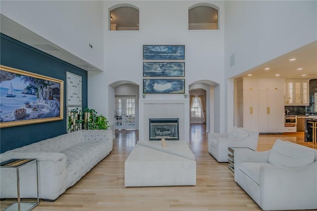 4 W Colonial Dr, Rogers, AR 72758 - living area featuring arched walkways, a high ceiling, light wood finished floors, and healthy amount of natural light