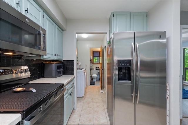3 Summit Dr, Holiday Island, AR 72631 - kitchen featuring stainless steel appliances, washing machine and dryer, light countertops, decorative backsplash, and light tile patterned floors
