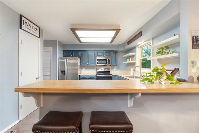 81 Overton Dr, Bella Vista, AR 72714 - kitchen with stainless steel appliances, blue cabinetry, a sink, light countertops, and a peninsula