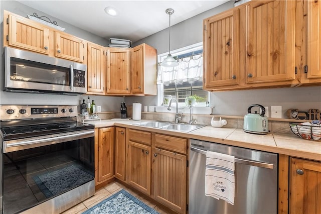 413 W Tahlequah St, Siloam Springs, AR 72761 - kitchen featuring appliances with stainless steel finishes, a sink, tile countertops, light tile patterned flooring, and decorative light fixtures