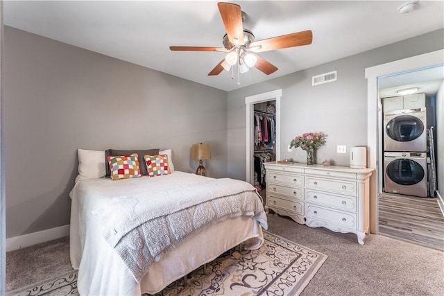 413 W Tahlequah St, Siloam Springs, AR 72761 - bedroom with stacked washer / drying machine, light carpet, a closet, a ceiling fan, and a spacious closet