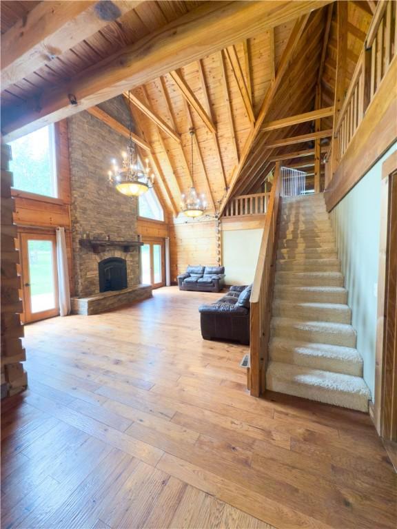 463 County Road 2281, Eureka Springs, AR 72631 - unfurnished living room with a chandelier, a fireplace, hardwood / wood-style floors, high vaulted ceiling, and wood ceiling with exposed beams