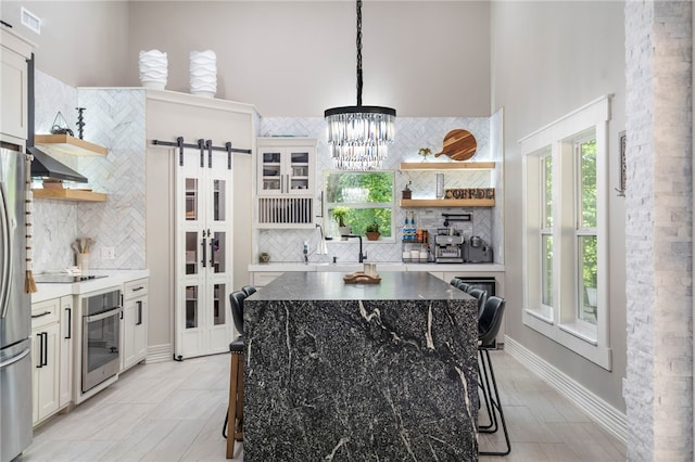 18097 Clear Water Rd, Fayetteville, AR 72704 - kitchen featuring open shelves, appliances with stainless steel finishes, decorative backsplash, a barn door, and a towering ceiling
