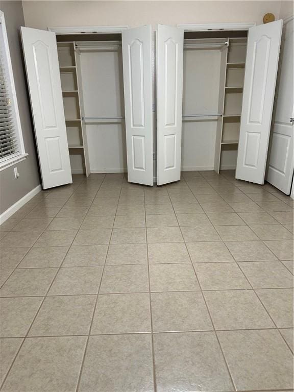 20944 Shady Grove Rd, Siloam Springs, AR 72761 - unfurnished bedroom with light tile patterned floors, baseboards, and two closets