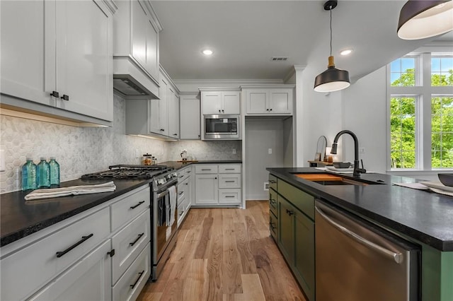 41 Westmorland Dr, Bella Vista, AR 72714 - kitchen featuring stainless steel appliances, dark countertops, a sink, light wood finished floors, and crown molding