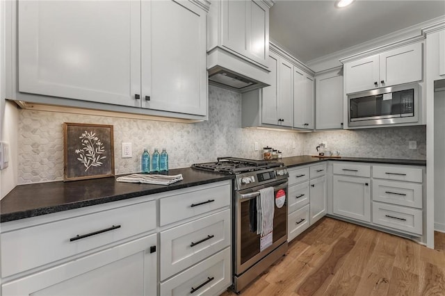 41 Westmorland Dr, Bella Vista, AR 72714 - kitchen with stainless steel appliances, light wood-style flooring, tasteful backsplash, dark countertops, and crown molding