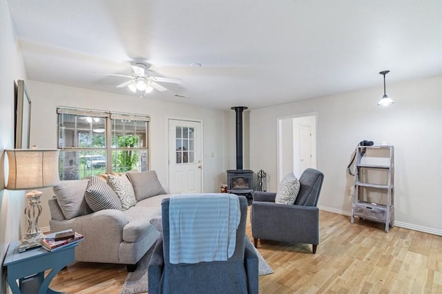 17171 Kincheloe Rd, Siloam Springs, AR 72761 - living area with a wood stove, ceiling fan, light wood-style flooring, and baseboards