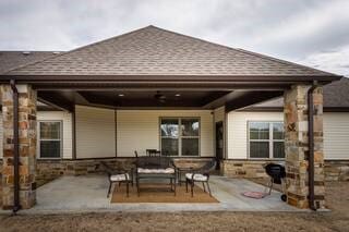 10211 Lydia Ln, Danville, AR 72833 - rear view of property featuring a shingled roof, stone siding, and a patio