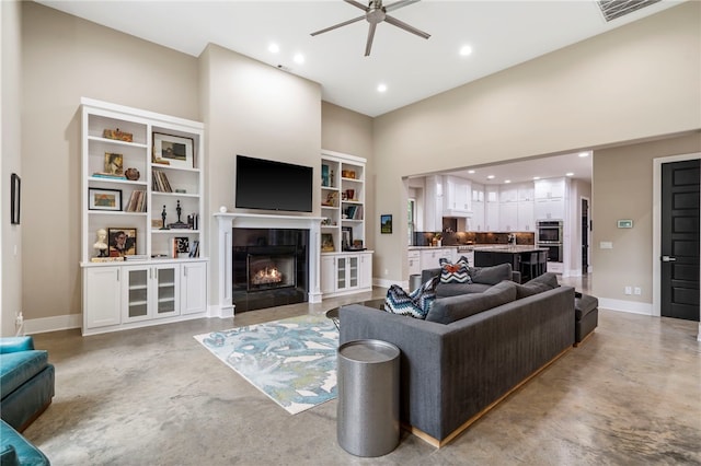 3634 Sugarberry Ln, Springdale, AR 72764 - living area featuring concrete floors, a ceiling fan, a towering ceiling, a tiled fireplace, and recessed lighting
