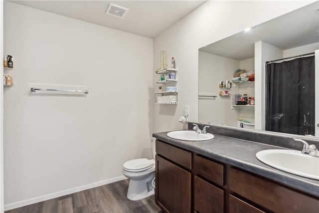 2409 S Silver St, Siloam Springs, AR 72761 - bathroom featuring wood finished floors, double vanity, toilet, and baseboards