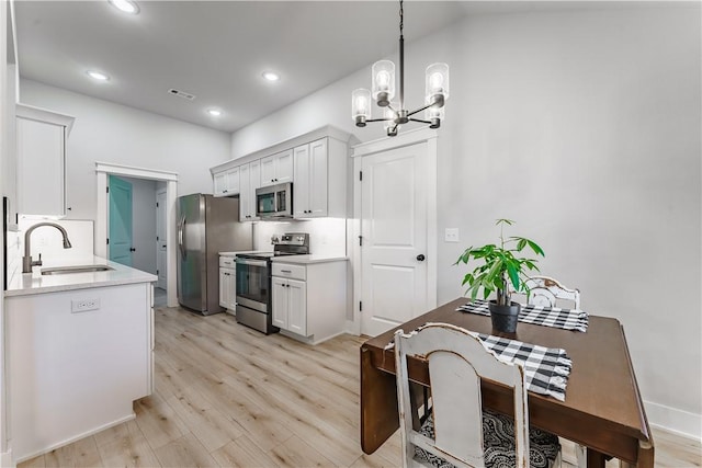 8 Grantham Dr, Bella Vista, AR 72714 - kitchen featuring stainless steel appliances, a sink, a chandelier, light wood finished floors, and light countertops