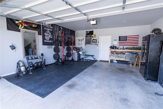 5803 SW Gentle Winds Ave, Bentonville, AR 72713 - garage with freestanding refrigerator, a garage door opener, and a workshop area